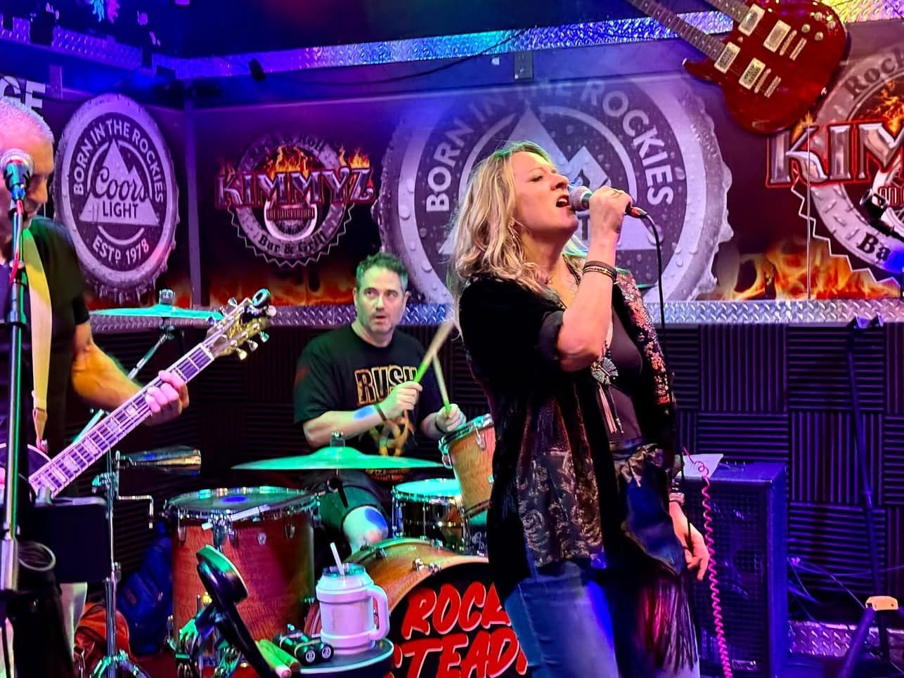 Rock Steady vocalist singing under colorful stage lights